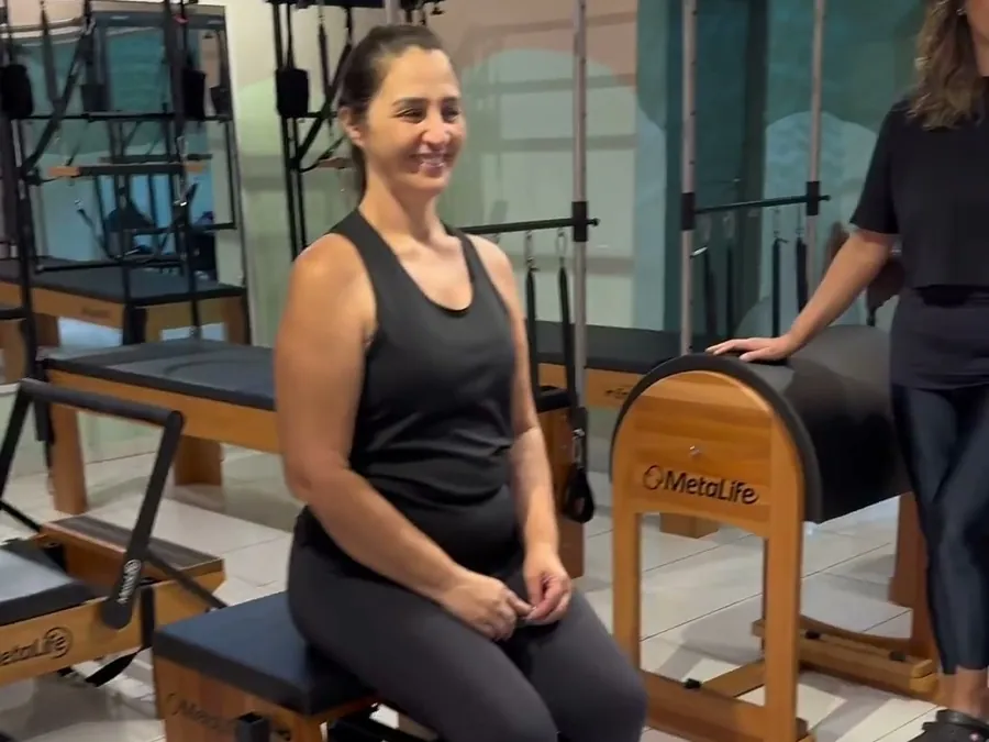 Aluna na chair do Nogueira Pilates ao lado da instrutora